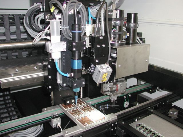 Máquina de impresión industrial depositando tinta conductora sobre placas para fabricar sensores estructurales impresos.